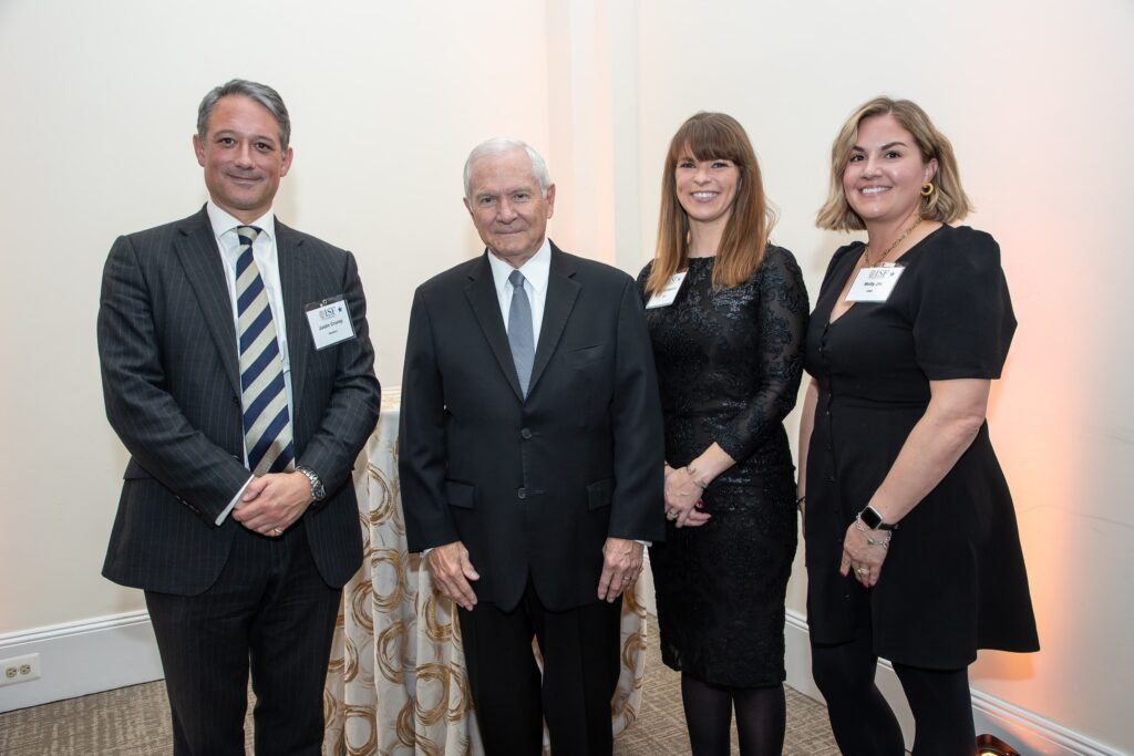 four people standing next to each other in front of a curtain