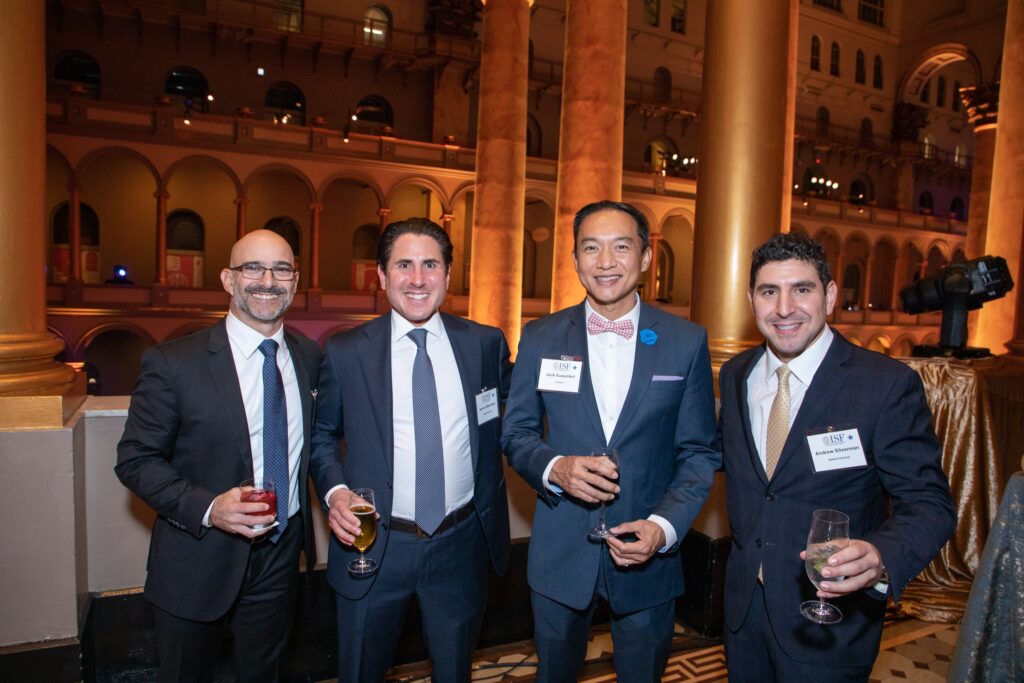 four men in suits and ties posing for the camera