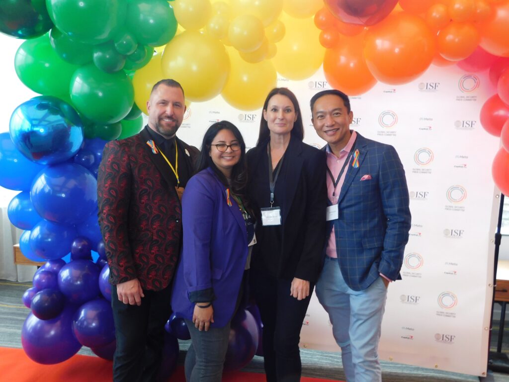 three people standing in front of a rainbow backdrop