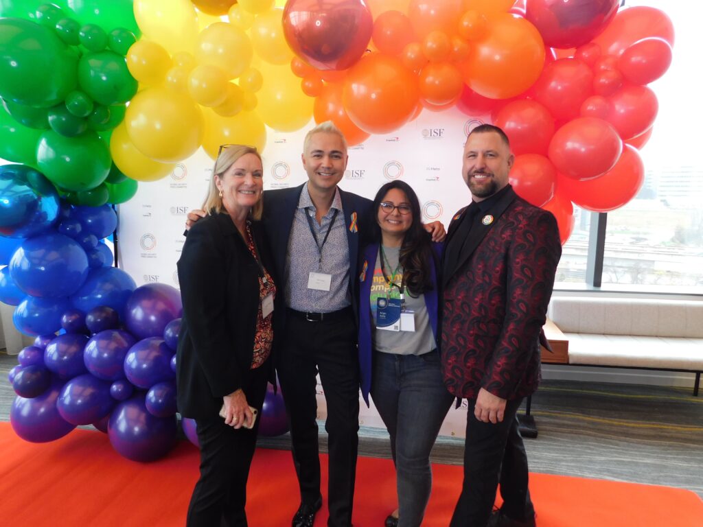three people standing in front of a backdrop with balloons
