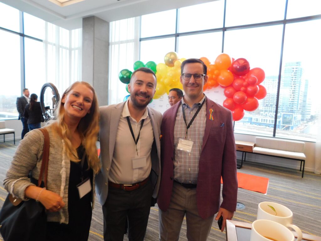 three people standing next to each other in front of large windows