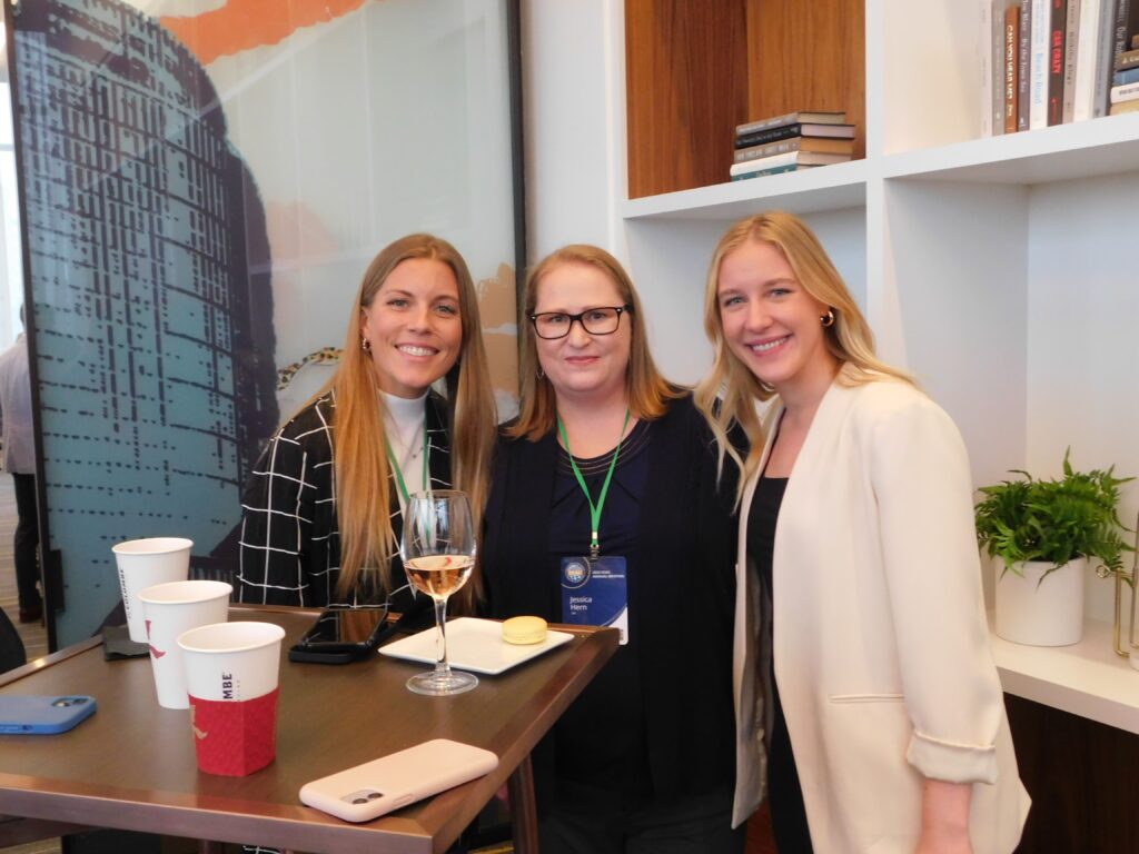 three women standing next to each other holding wine glasses