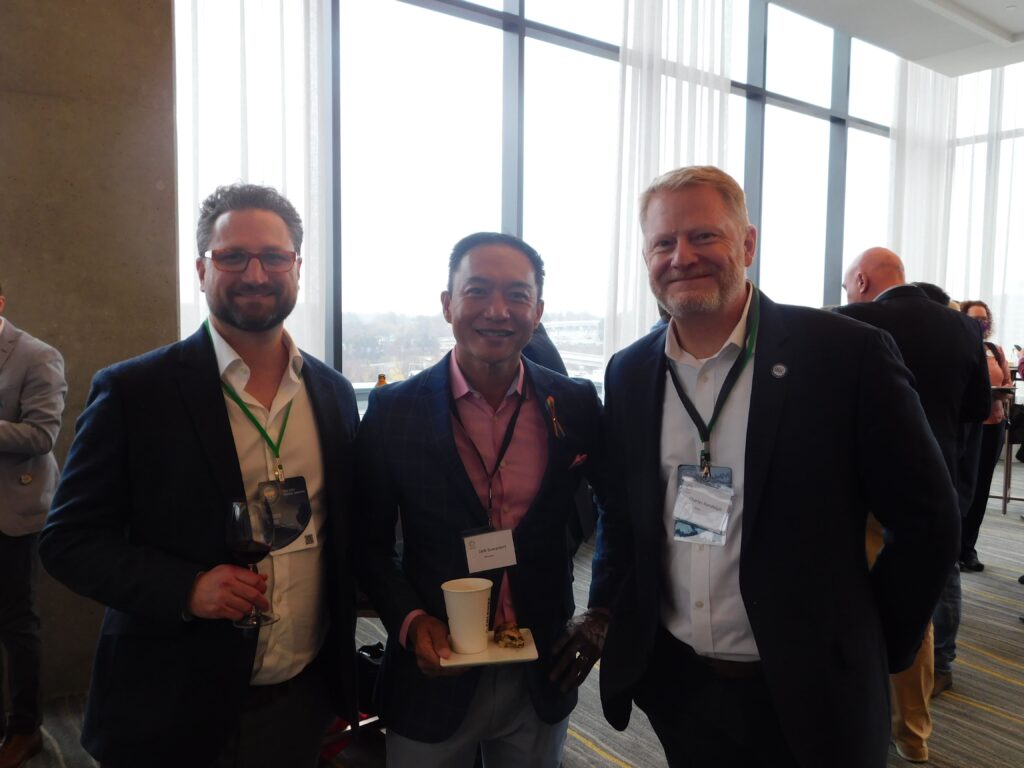 three men standing next to each other in front of a window