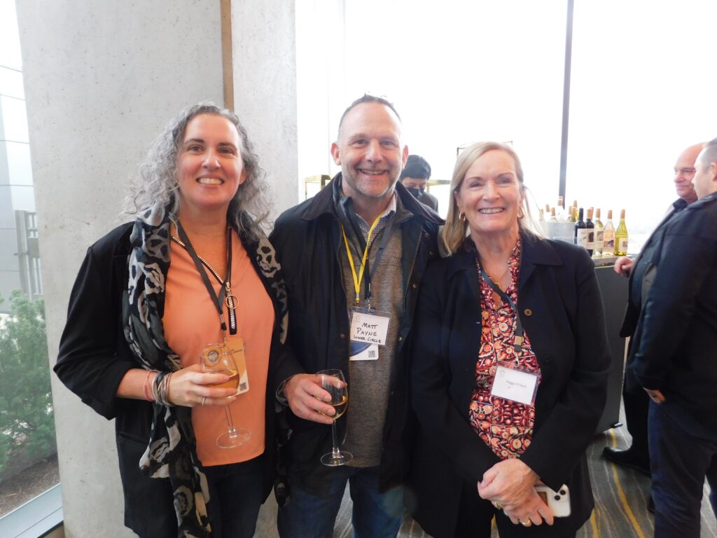 three people standing next to each other holding wine glasses