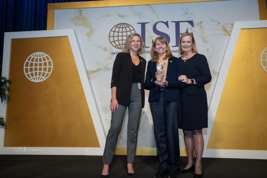 three women standing next to each other holding an award