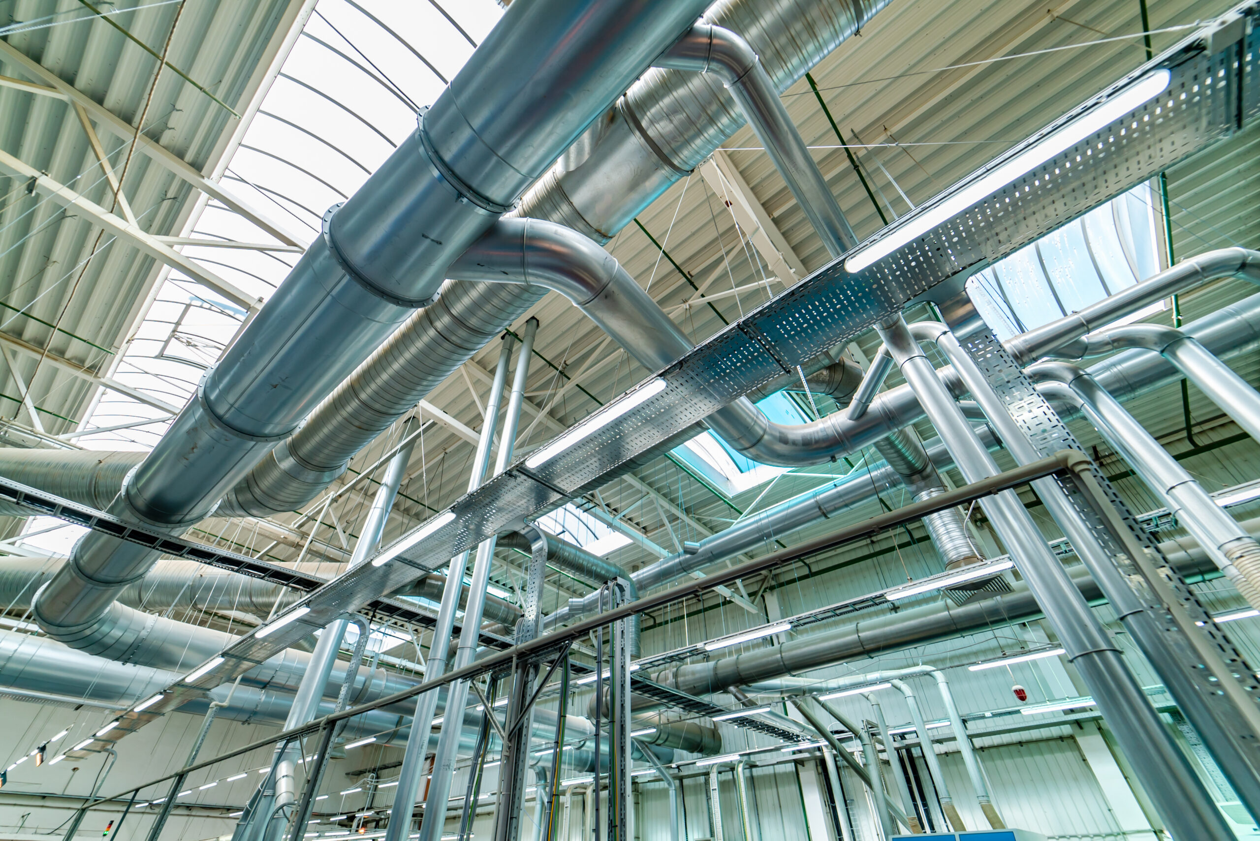 a large room with metal pipes and a skylight