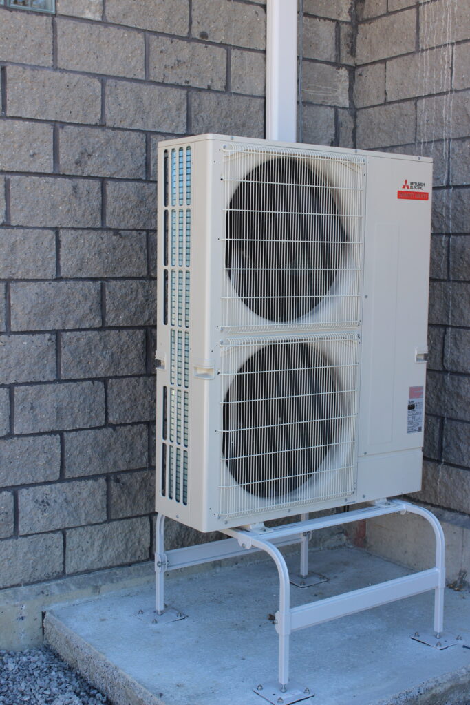 a white air conditioner sitting on the side of a building