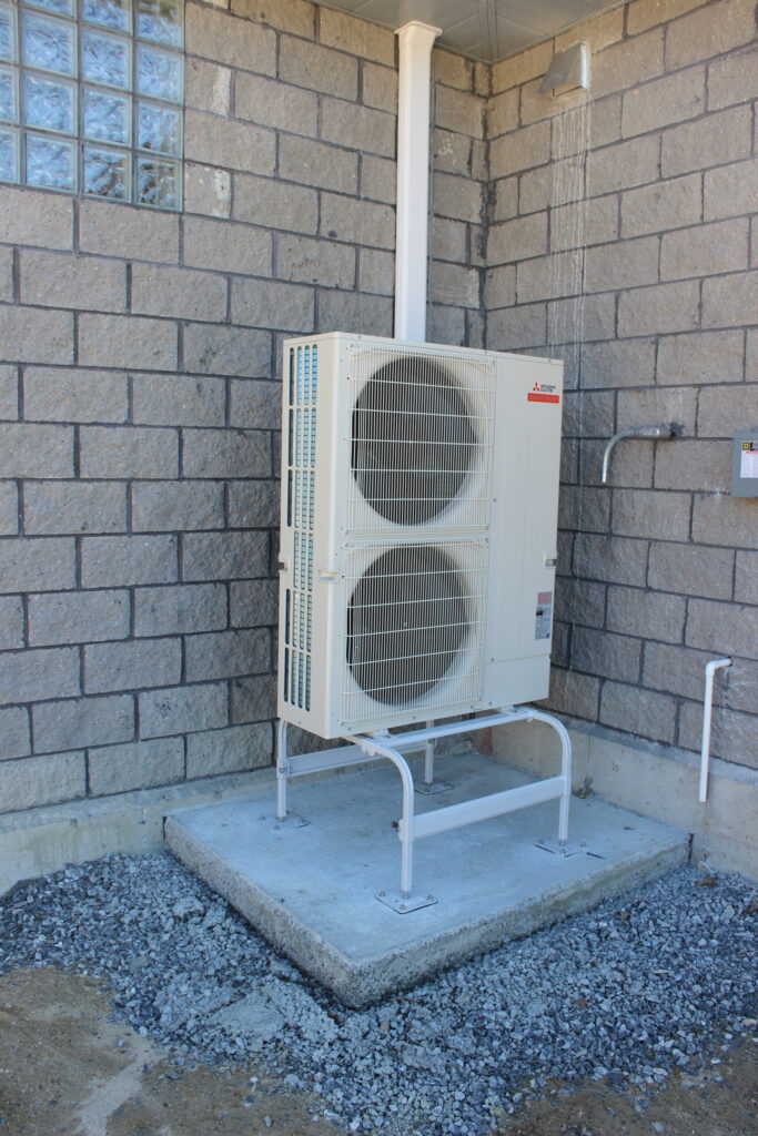a white air conditioner sitting on the side of a building