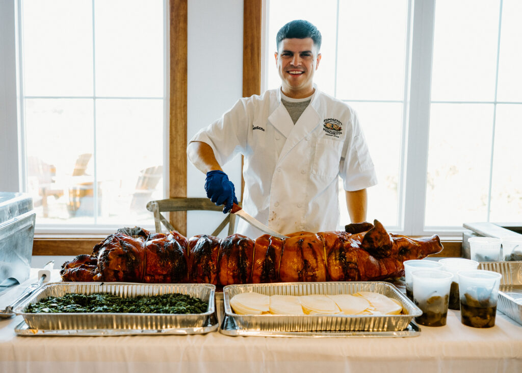 A caterer with a roasted pig ahead of carving for guests during cocktail hour in the sunporch at King Cole Farm.
