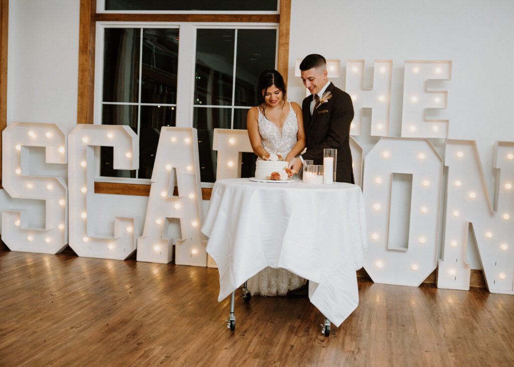 A Bride and Groom cutting the cake in the sunporch of the pole barn at King Cole Farm