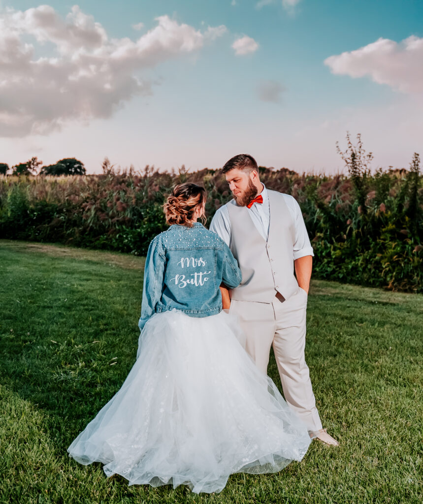 A bride and groom against the corn field in the back patio of the Pole barn at King Cole Farm.