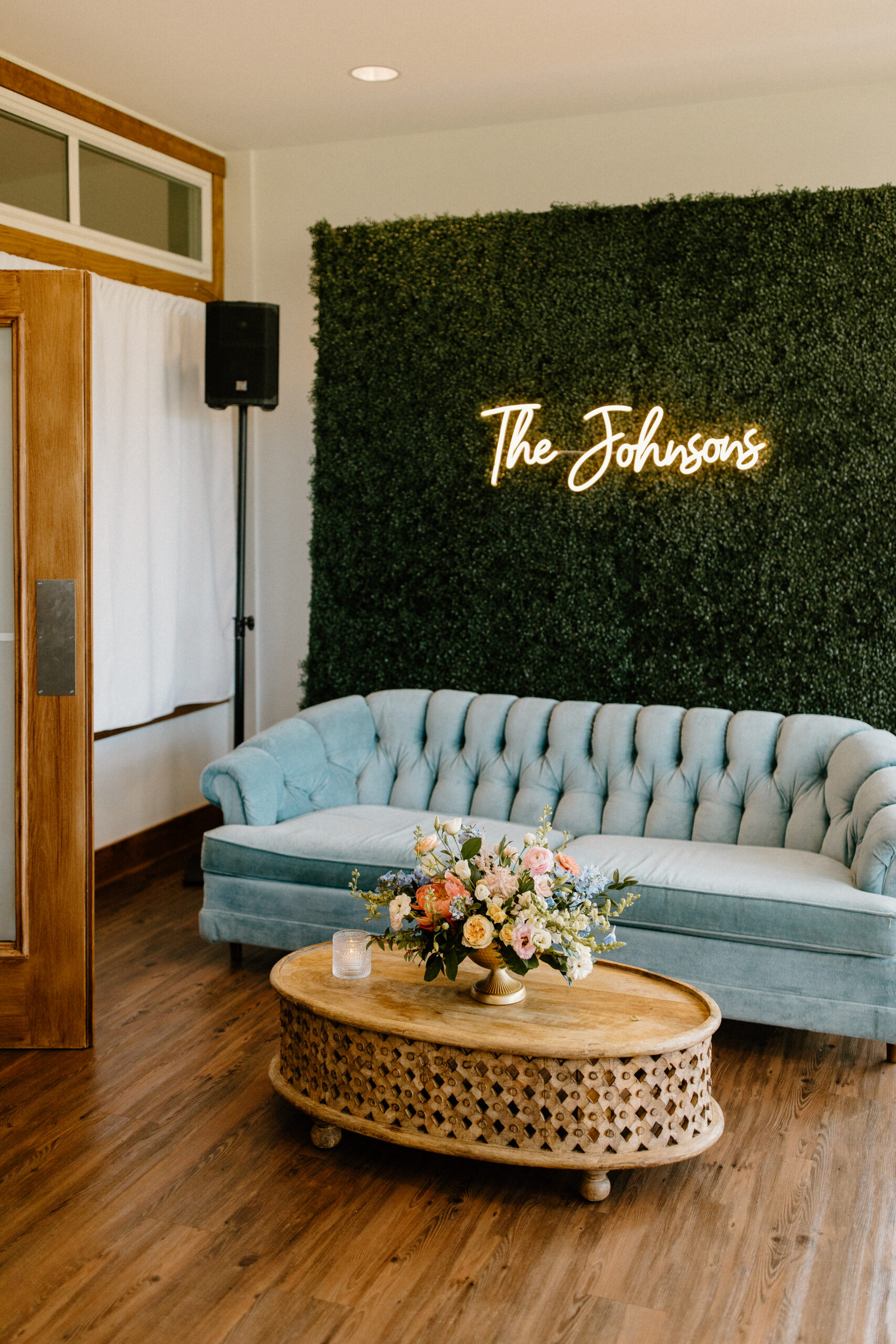 A couch, coffee table, and flower arrangement set up as a photo op in the sunporch of the Pole Barn at King Cole Farm