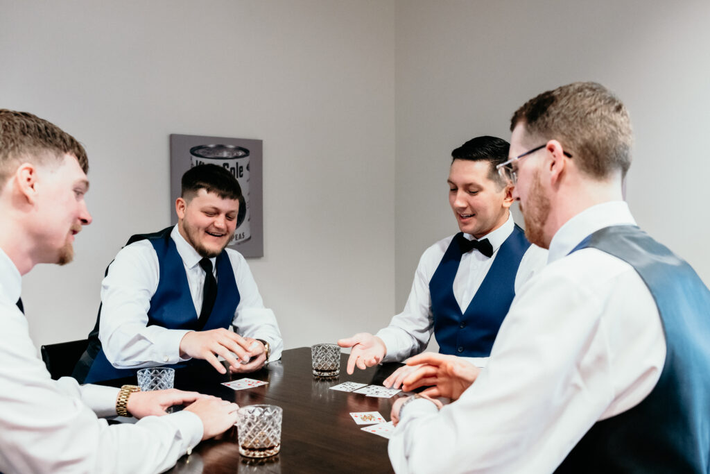 A groom and his groomsmen playing cards in the Groomsmen's Lodge in the Pole Barn at King Cole Farm.