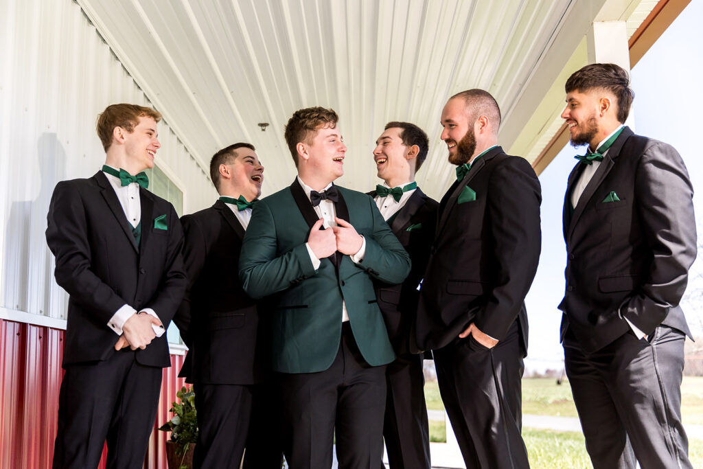 A groom and his groomsmen standing outside of the groom's lodge outside of the Pole Barn at King Cole Farm.