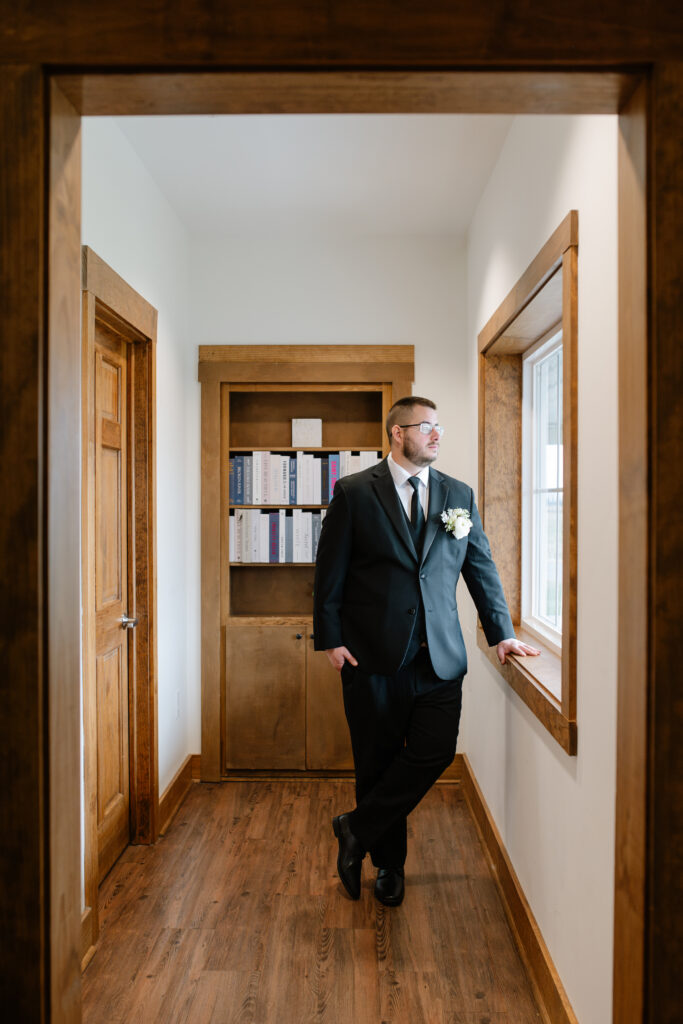 A groom standing in the hallway outside of the groom's lodge in the Pole Barn at King Cole Farm.