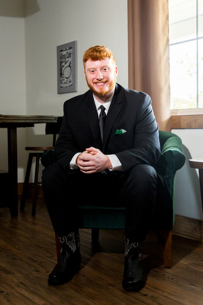 A groom sitting in a chair in the groom's lodge in the Pole Barn at King Cole Farm.