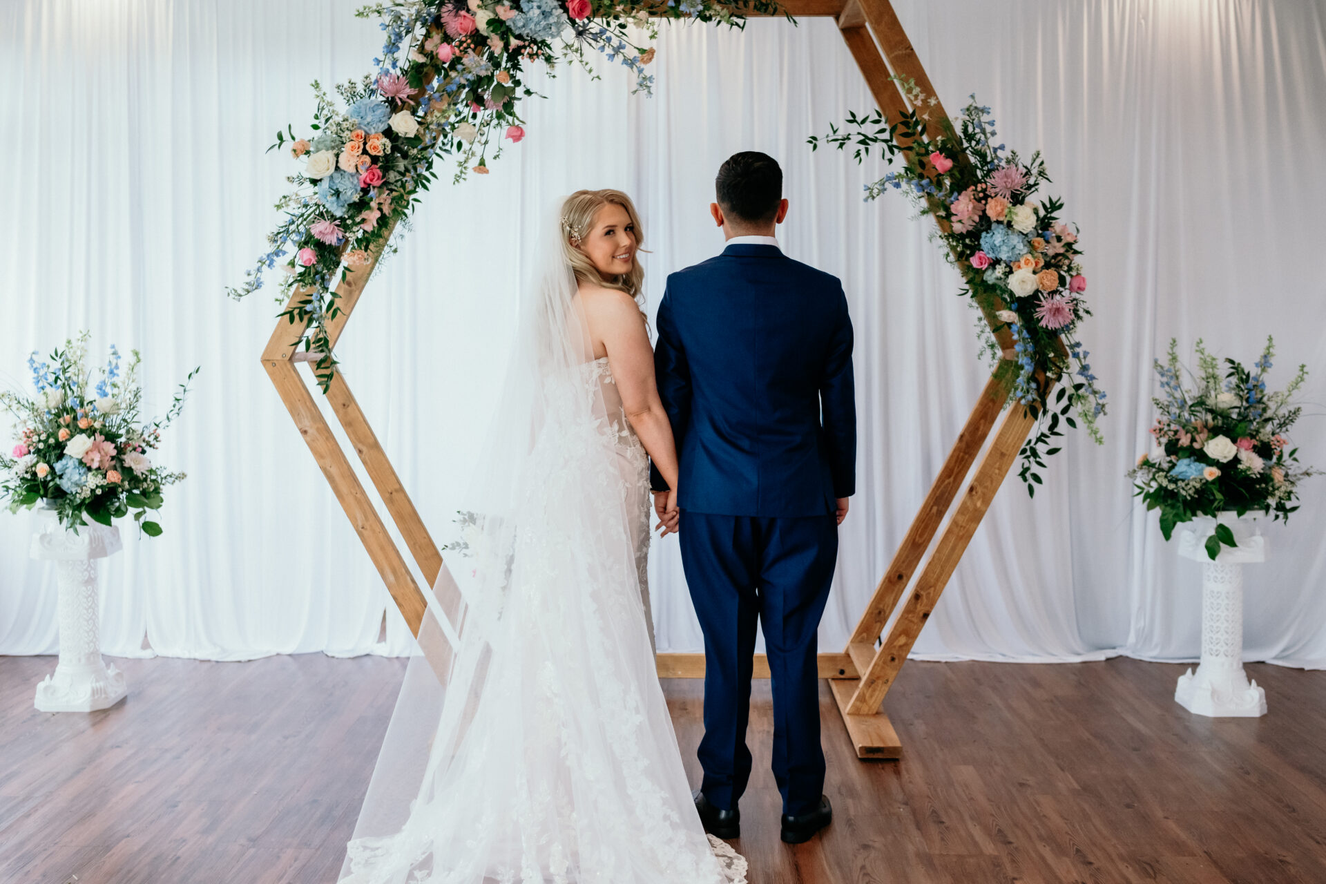 A bride and groom standing in front of their ceremony space in the sunporch at King Cole Farm.