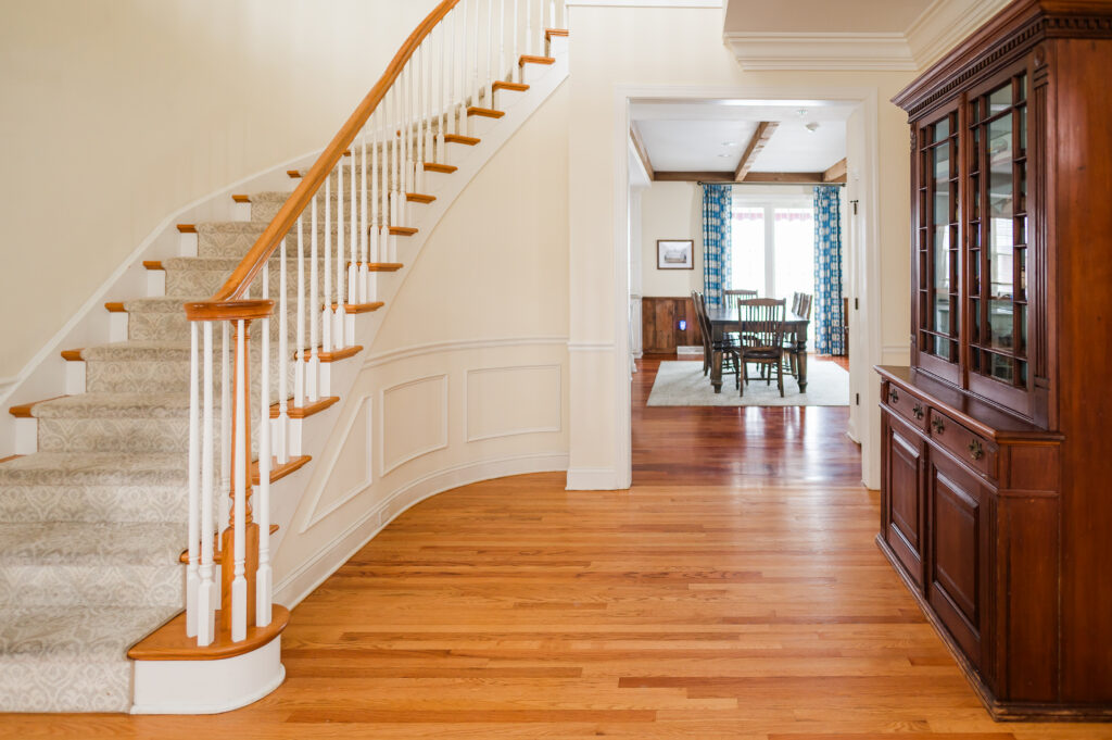 Image features the hallway next to the staircase with a bookshelf and looking into the kitchen in The Residence at King Cole Farm.