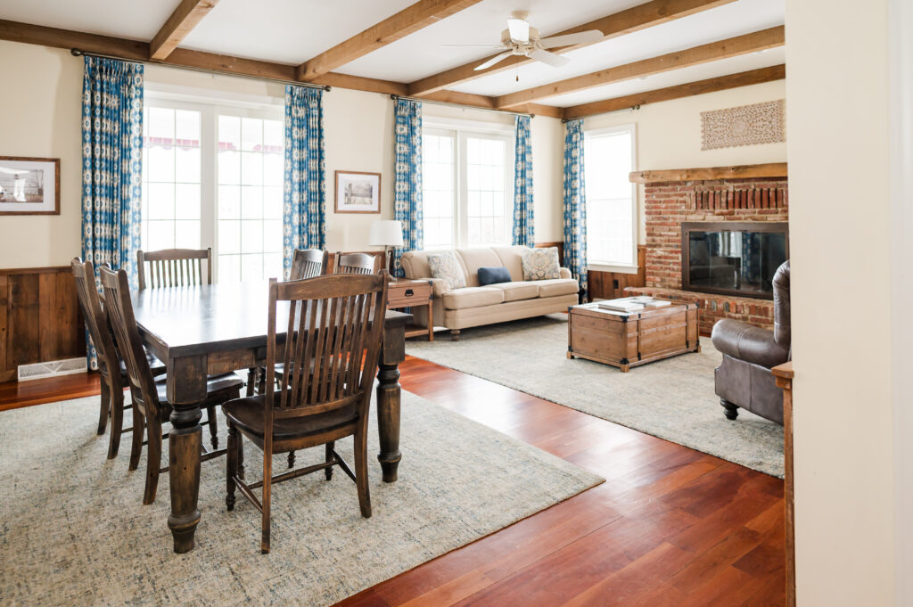 Image including a coffee table, fire place, side table, couch, dining table with chairs, tv, and curtains in The Residence at King Cole Farm.