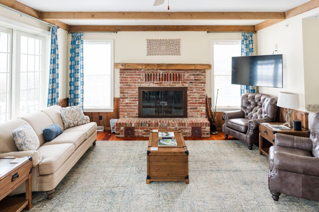 Image including a coffee table, fire place, side table, couch, chairs, tv, and curtains in The Residence at King Cole Farm.