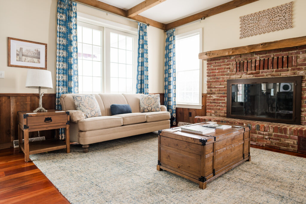 Image including a coffee table, fire place, side table, couch, tv, and curtains in The Residence at King Cole Farm.
