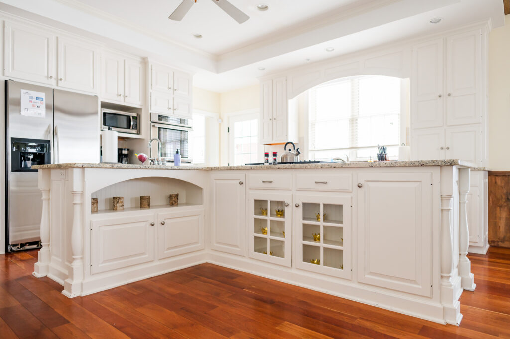 Image including the kitchen countertops and shelves, kitchen island with sink and range, refrigerator and freezer, coffee nook, and double ovens, windows and doors in the Residence at King Cole Farm.