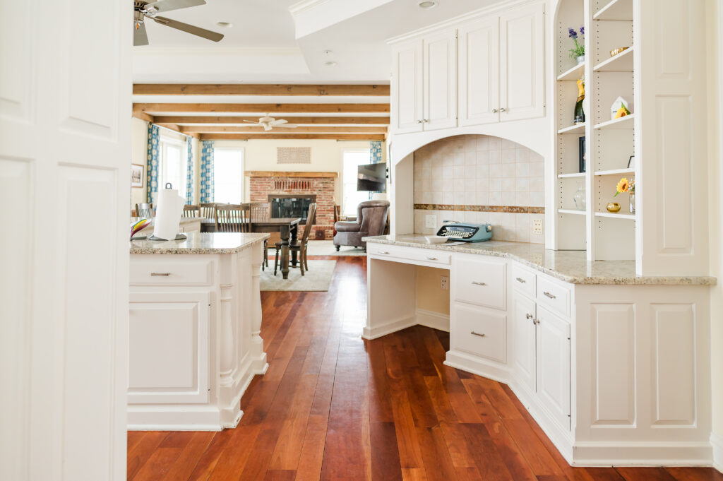 Image including the kitchen countertops, typewriter book, kitchen island, decorative shelves, and entrance to the living room in the Residence at King Cole Farm.