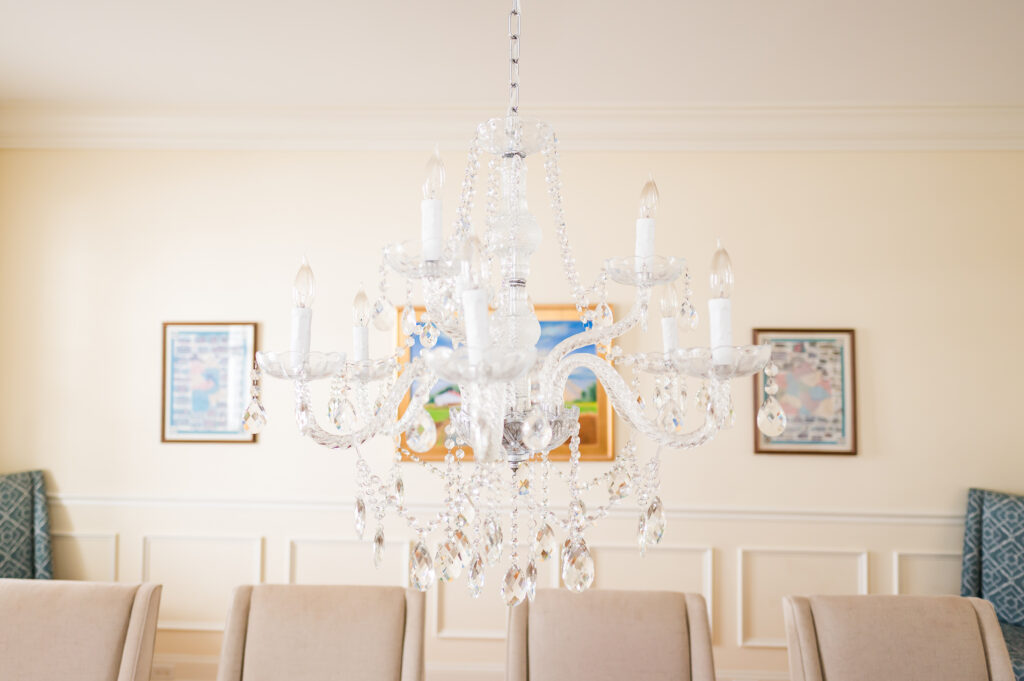 An image including the chandelier, wall art, and chairs in the formal dining room in The Residence at King Cole Farm.