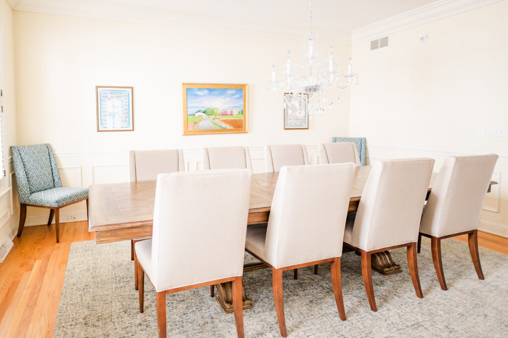 An image of the formal dining room including chairs, a table, wall art, and a chandelier at The Residence at King Cole Farm.