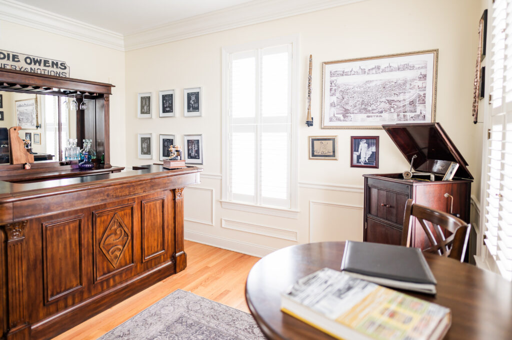 Image including a bar, mirror, wall art, instruments, old record player, and a high top table with chairs in the Prohibition Bar in The Residence at King Cole Farm.