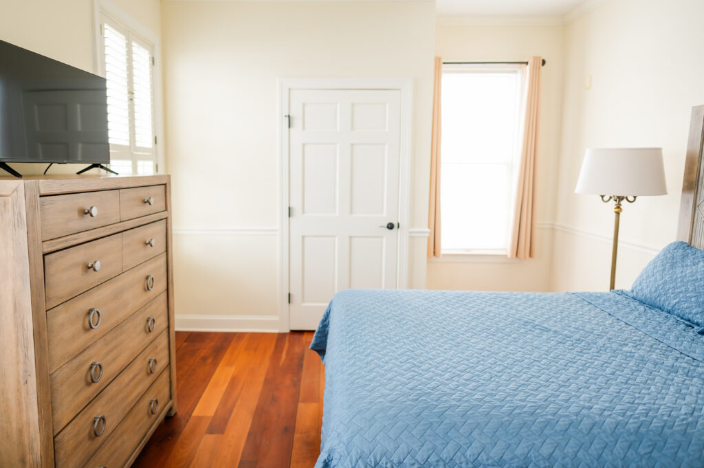 Image featuring queen size bed, dresser with tv, closet, and windows in the ADA Bedroom at The Retreat at King Cole Farm.