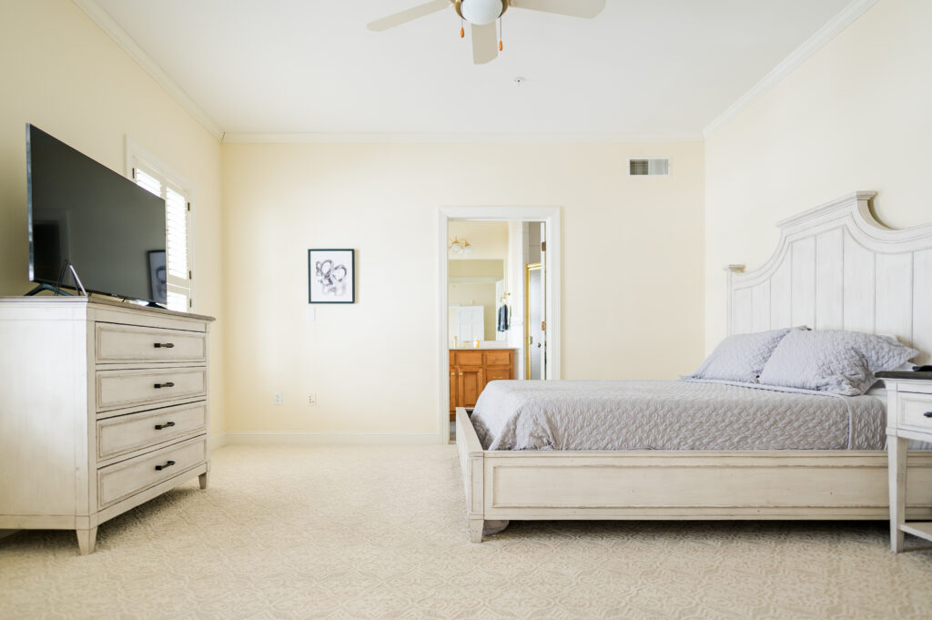 Image featuring the king bed, dresser with TV, bathroom entrance, and wall art in the Sunset Bedroom in the Retreat at King Cole Farm.