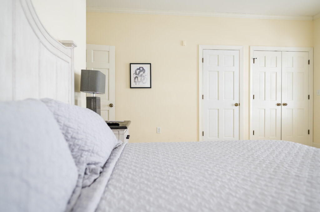 Image featuring the king bed, side table, art, and closets in the Sunset Bedroom in the Retreat at King Cole Farm.