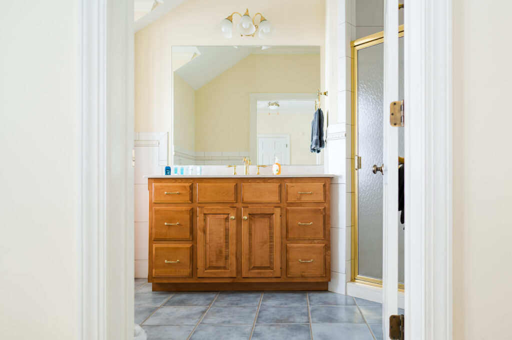 Image featuring the entrance to the bathroom, shower, sink vanity, and mirror in the Sunset Bathroom in the Retreat at King Cole Farm.