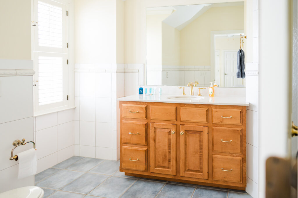 Image featuring the sink vanity, mirror, and window in the Sunset Bathroom in the Retreat at King Cole Farm.