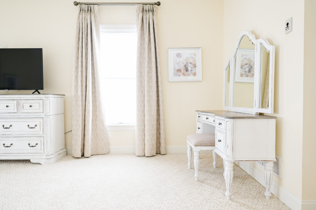 Image of the dresser, tv, window with curtains, and vanity in the bridal suite bedroom at King Cole Farm
