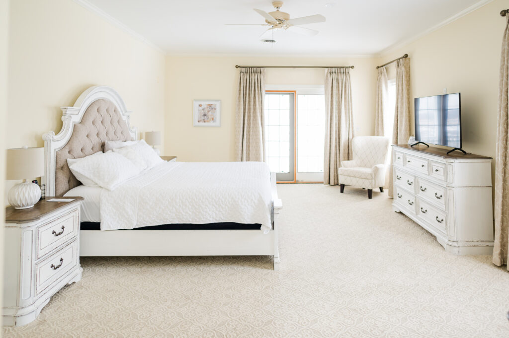Image of the bed, chair, dresser, and door to the balcony in the bridal suite bedroom at King Cole Farm