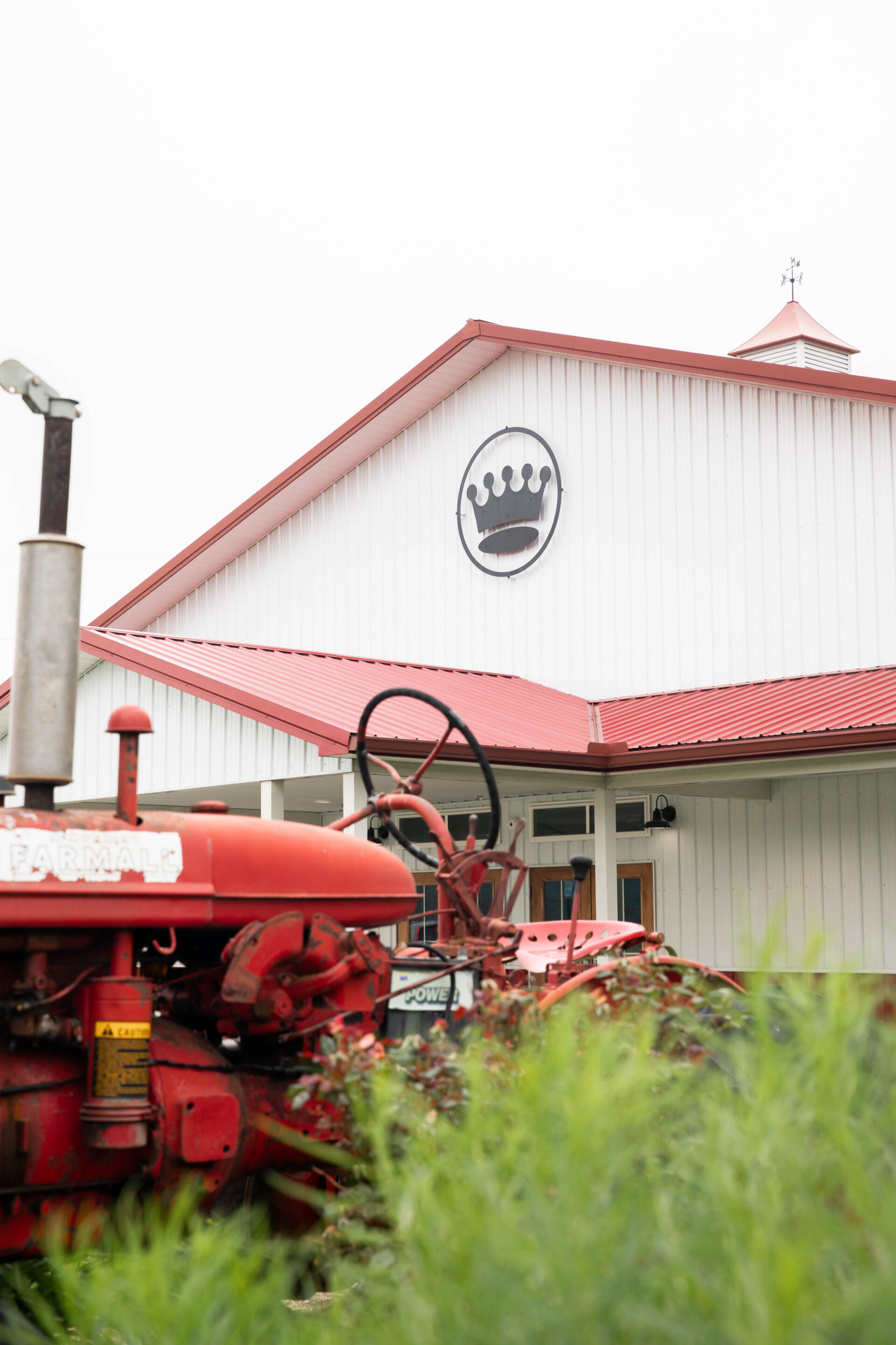 Red tractor and green bushes in front of the Pole Barn at King Cole Farm