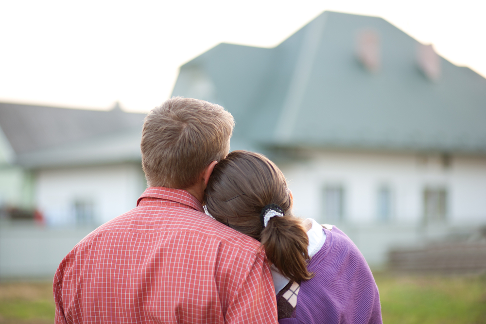 a man and a woman standing in front of a house