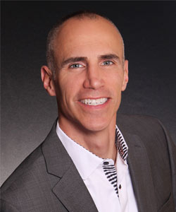 a man in a suit and tie smiling at the camera