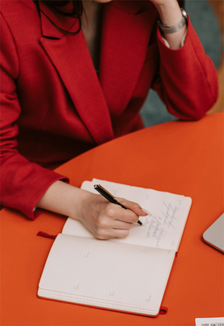 E-Closing a woman in a red jacket writing on a notebook