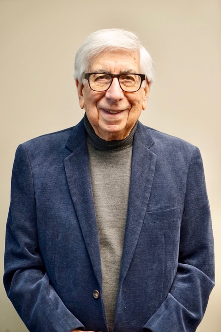 man with white hair, blue blazer, and glasses
