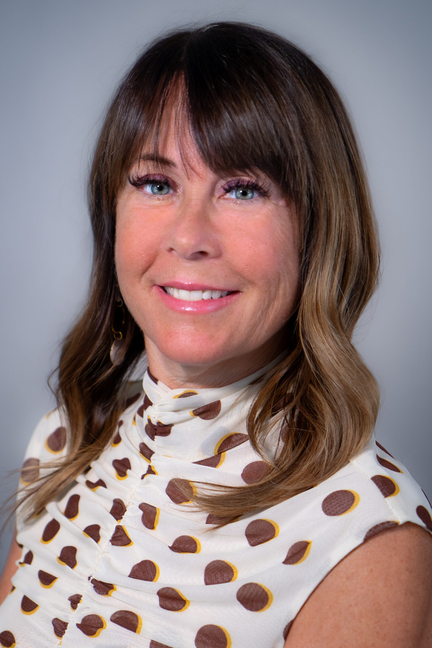 a woman with long hair wearing a polka dot shirt