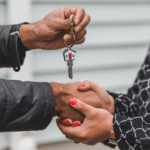 two people shaking hands with a house key