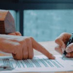 a couple of people sitting at a table signing papers