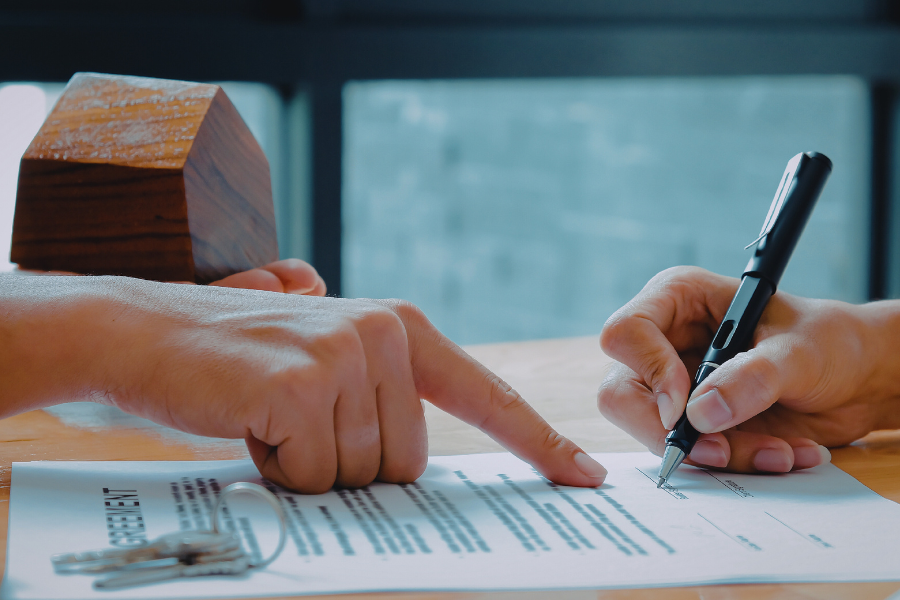 a couple of people sitting at a table signing papers