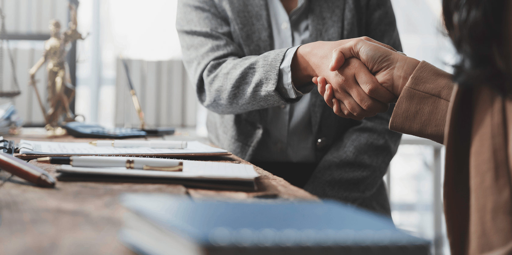 two people shaking hands over a desk
