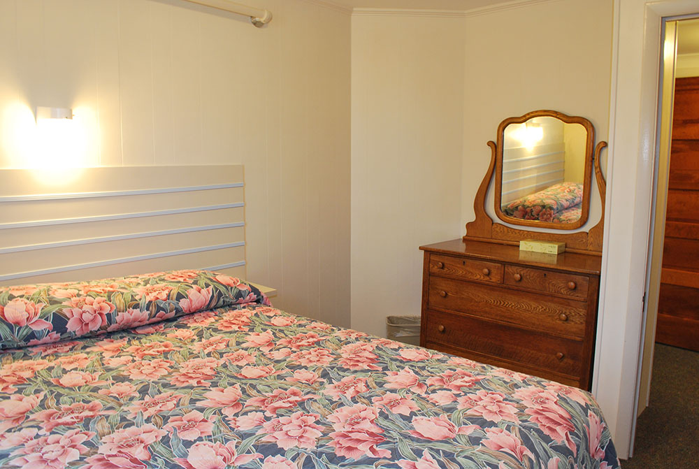 a bedroom with a bed, dresser and mirror