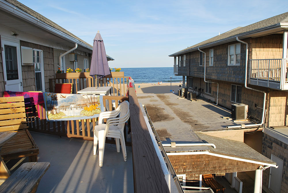 a balcony with chairs and tables overlooking the ocean