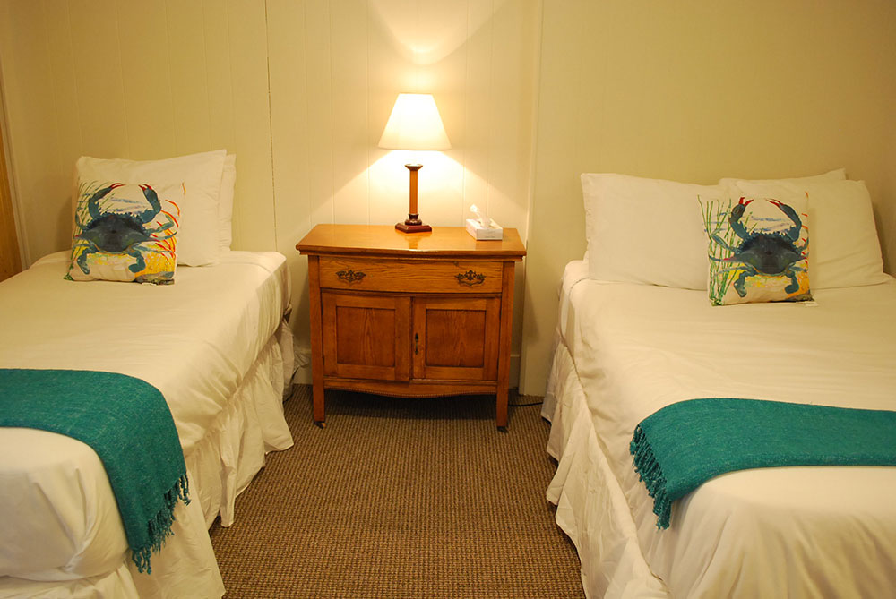 two beds with white sheets and green blankets
